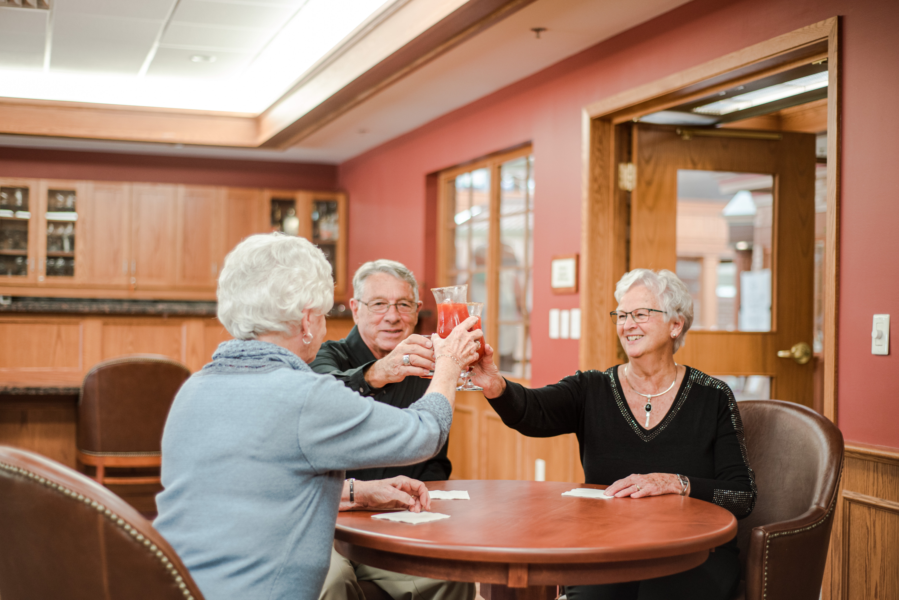 Three residents cheersing with drinks in the Social Club