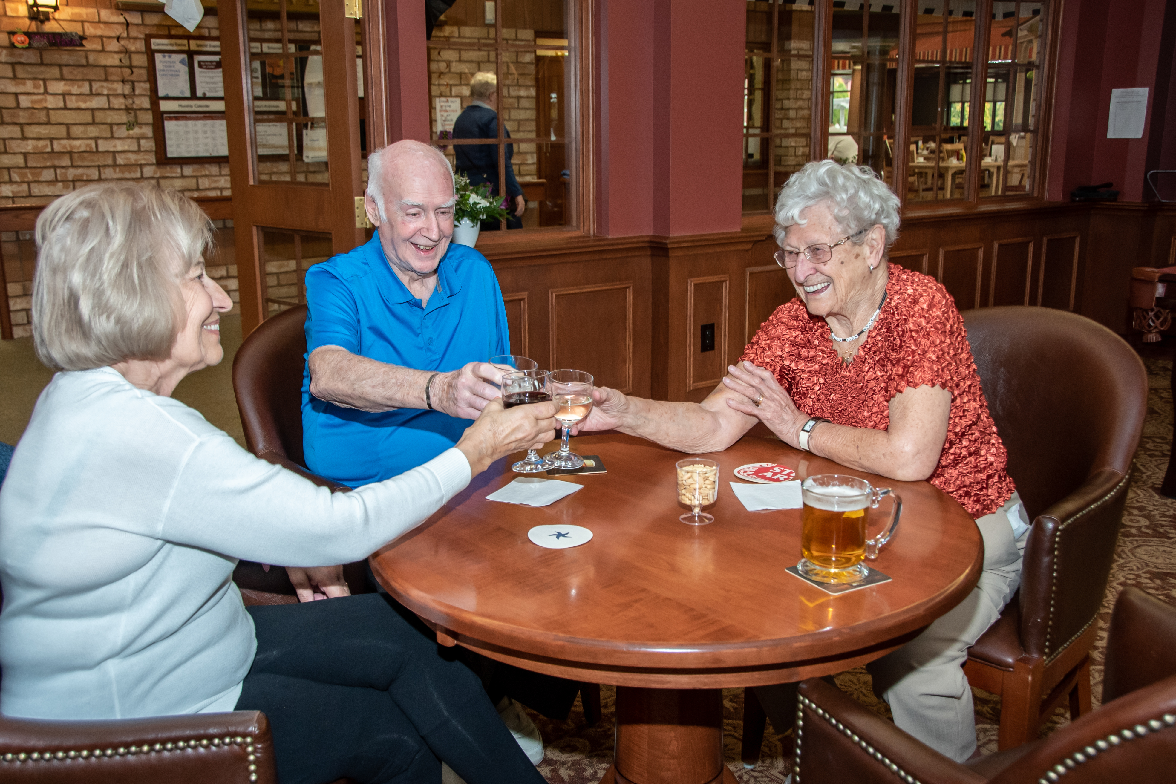 Three residents in the Social Club cheersing with their drinks