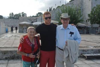 Two residents and a team member posing for a photo amid ruins in Greece