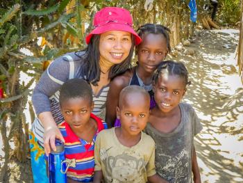 Team member with her arms around a group of small children in Haiti