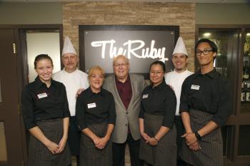 Ron Schlegel and team members standing in front of a sign for The Ruby restaurant