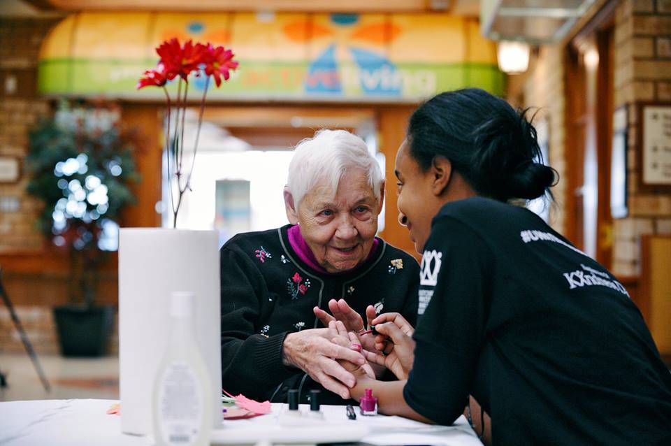 Volunteer paints senior woman's nails on the Village Main Street