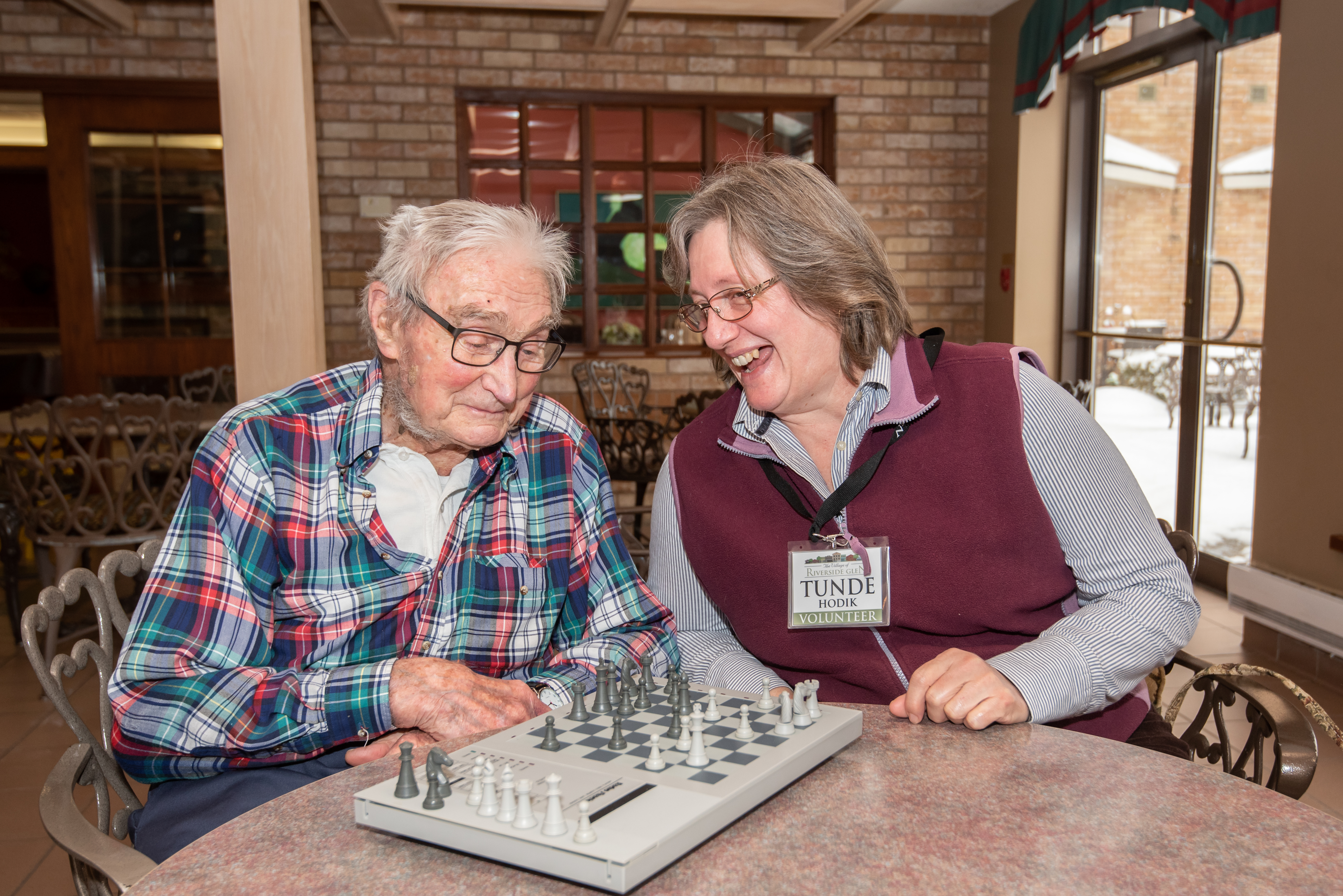 Village volunteer playing chess with senior man in the cafe