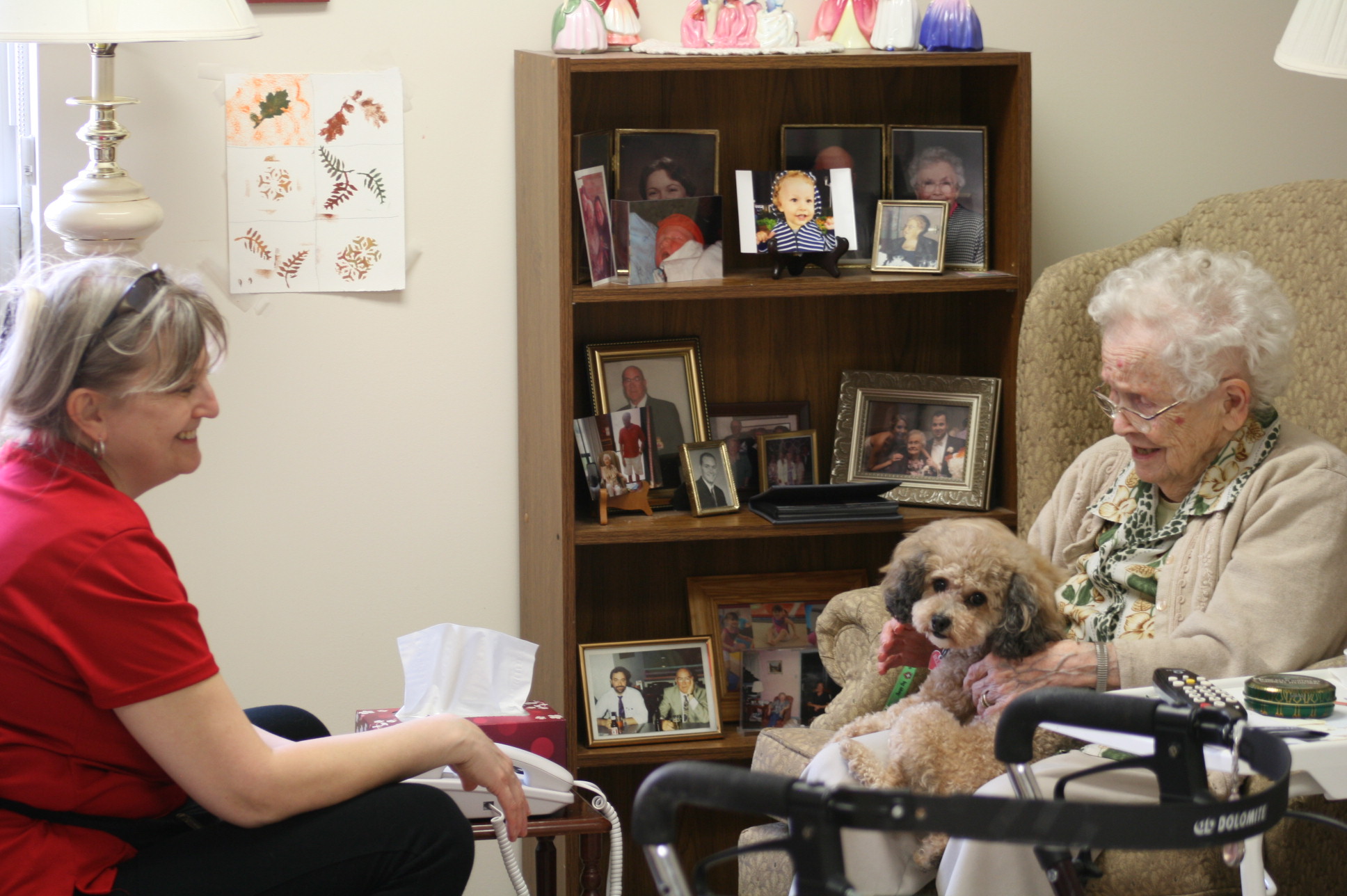 Resident with dog on her lap visiting with a team member